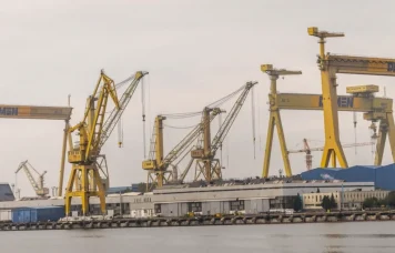 Macaralele Șantierului Naval Mangalia oglindite în apă, într-o zi înnorată